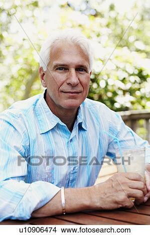 Picture - Portrait of a mature man holding a glass of juice. Fotosearch