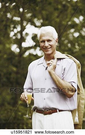 Stock Image - Portrait of a mature man holding a glass of juice. Fotosearch
