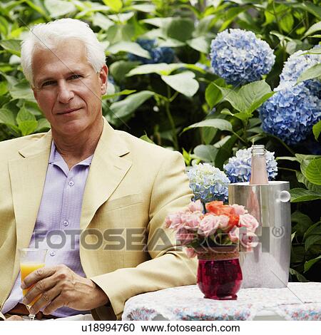 Stock Image - Portrait of a mature man holding a glass of juice. Fotosearch