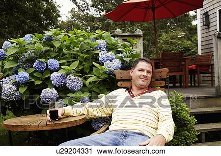 Portrait of a mature man holding a glass and sitting on a chair View Large Photo Image Stock Image - Portrait of a mature man holding a glass and sitting on a chair. Fotosearch
