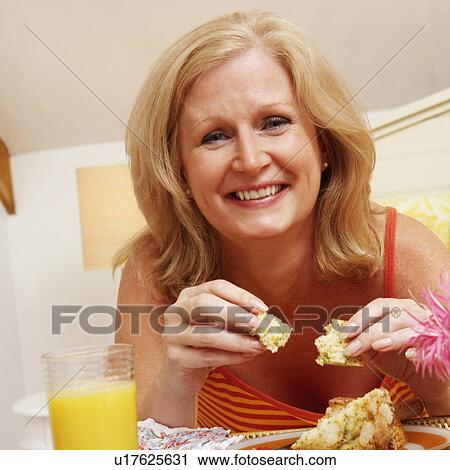 Portrait of a mature woman having breakfast in bed View Large Photo Image Stock Image - Portrait of a mature woman having breakfast in bed. Fotosearch