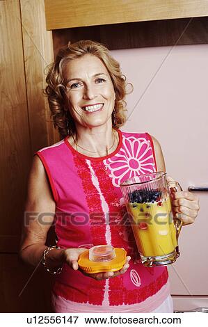 Portrait of a mature woman holding a jug of mango shake View Large Photo Image Stock Photo - Portrait of a mature woman holding a jug of mango shake. Fotosearch