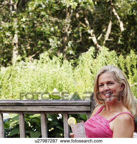 Portrait of a mature woman holding a glass of lemonade and smiling View Large Photo Image Stock Photo - Portrait of a mature woman holding a glass of lemonade and smiling. Fotosearch