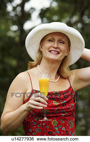 Stock Photograph - Portrait of a mature woman holding a glass of juice. Fotosearch