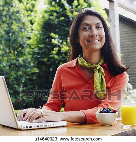 Stock Image - Portrait of a mature woman working on a laptop. Fotosearch