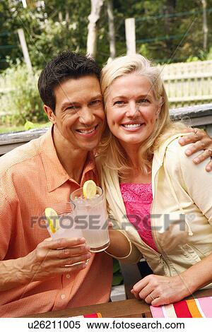 Stock Photography - Portrait of mature couple toasting their glasses of lemon juice and smiling. Fotosearch