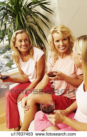 Three women sitting together and holding glasses of wine View Large Photo Image Stock Image - Three women sitting together and holding glasses of wine. Fotosearch