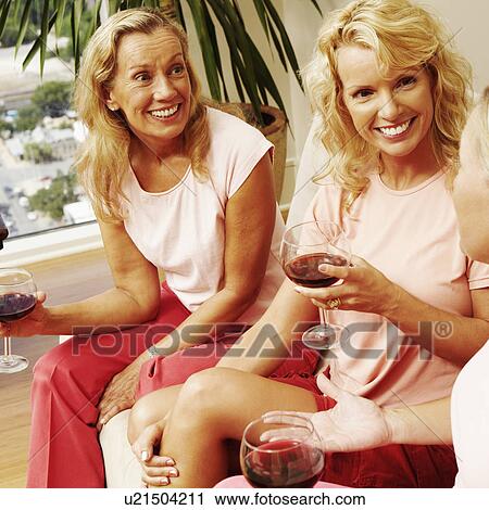 Three women sitting together and holding glasses of wine View Large Photo Image Stock Image - Three women sitting together and holding glasses of wine. Fotosearch