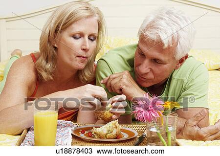 Close-up of a mature couple having breakfast in bed View Large Photo Image Stock Image - Close-up of a mature couple having breakfast in bed. Fotosearch