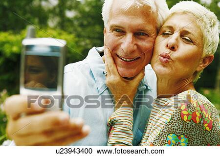Close-up of a mature man and a senior woman taking a picture of themselves View Large Photo Image Stock Image - Close-up of a mature man and a senior woman taking a picture of themselves. Fotosearch