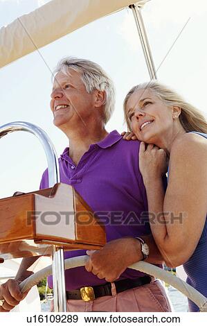 Stock Photo - Mature couple standing in a boat and smiling. Fotosearch