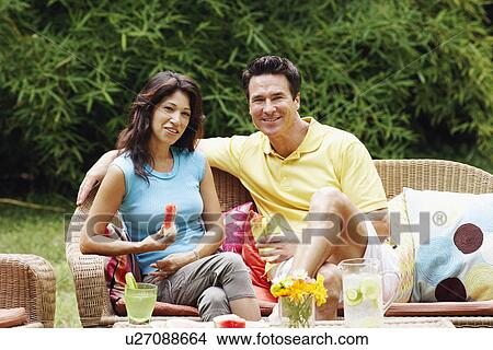 Mature man holding a glass of lemonade with a mature woman holding a slice of water melon beside him View Large Photo Image Picture - Mature man holding a glass of lemonade with a mature woman holding a slice of water melon beside him. Fotosearch
