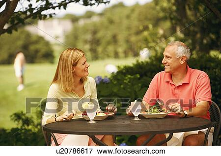 Mature man with a mid adult woman sitting at the table with plates of salad in front of them View Large Photo Image Stock Photo - Mature man with a mid adult woman sitting at the table with plates of salad in front of them. Fotosearch