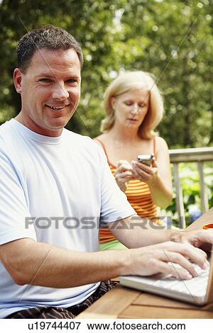 Portrait of a mature man smiling with a mature woman in the background View Large Photo Image Stock Photo - Portrait of a mature man smiling with a mature woman in the background. Fotosearch