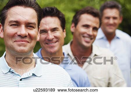 Portrait of a mature man smiling with his friends in the background View Large Photo Image Stock Photo - Portrait of a mature man smiling with his friends in the background. Fotosearch
