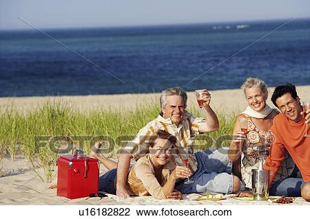 Portrait of two mature couples sitting on the beach and holding champagne flutes View Large Photo Image Stock Image - Portrait of two mature couples sitting on the beach and holding champagne flutes. Fotosearch