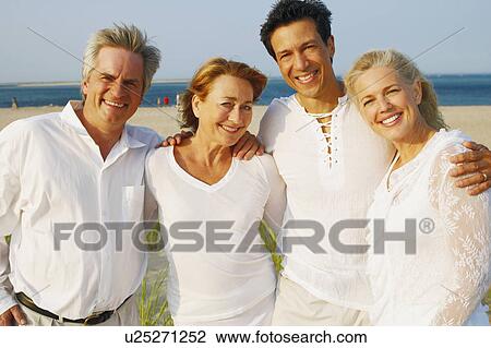 Portrait of two mature couples standing with their arms around each other on the beach View Large Photo Image Stock Image - Portrait of two mature couples standing with their arms around each other on the beach. Fotosearch