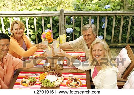 Stock Image - Portrait of two mature couples toasting glasses of lemonade. Fotosearch