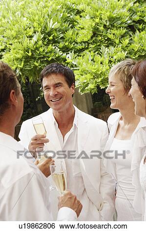 Stock Photograph - Two mature couples celebrating with champagne. Fotosearch