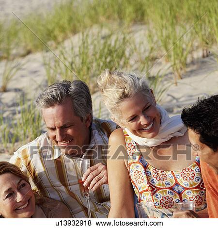 Two mature couples sitting on the beach and smiling View Large Photo Image Stock Photo - Two mature couples sitting on the beach and smiling. Fotosearch