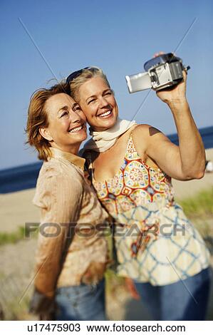Two mature women taking a picture of themselves on the beach View Large Photo Image Stock Image - Two mature women taking a picture of themselves on the beach. Fotosearch
