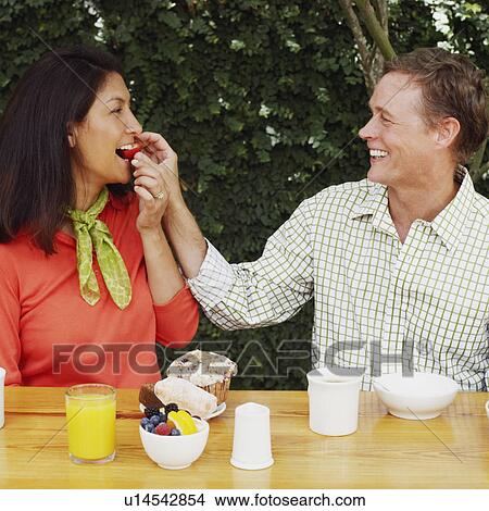 Close-up of a mature man feeding a strawberry to a mature woman View Large Photo Image Picture - Close-up of a mature man feeding a strawberry to a mature woman. Fotosearch