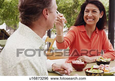 Close-up of a mature woman feeding a mature man with chopsticks View Large Photo Image Stock Photograph - Close-up of a mature woman feeding a mature man with chopsticks. Fotosearch