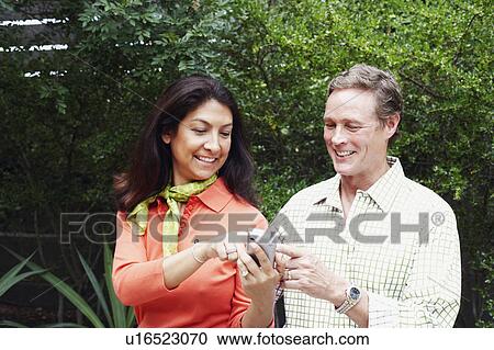 Stock Image - Close-up of a mature woman showing a mobile phone to a mature man. Fotosearch