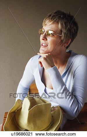 Stock Image - Close-up of a mature woman sitting with her hand on her chin. Fotosearch