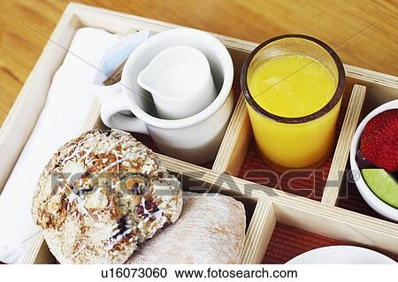 Stock Image - High angle view of muffins and a glass of orange juice in a breakfast tray. Fotosearch