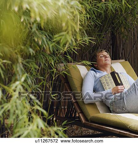 Stock Image - Mature woman sleeping on a lounge chair. Fotosearch