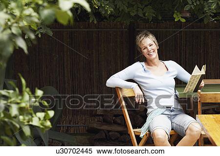 Stock Photography - Portrait of a mature woman holding a book and smiling. Fotosearch