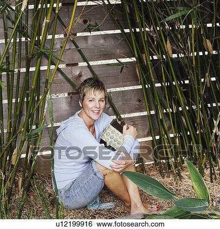 Stock Photograph - Portrait of a mature woman hugging her knees. Fotosearch
