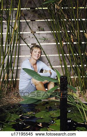Stock Photography - Portrait of a mature woman hugging her knees. Fotosearch