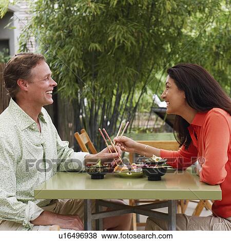 Stock Photo - Side profile of a mature couple sitting at a table and smiling. Fotosearch