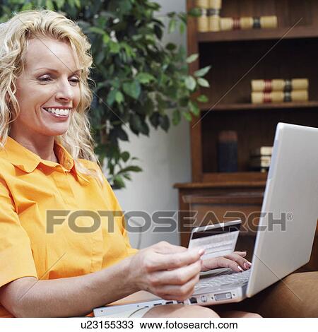 Businesswoman using a laptop and holding a credit card View Large Photo Image Stock Image - Businesswoman using a laptop and holding a credit card. Fotosearch