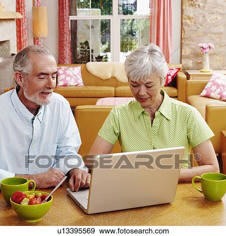 Mature man and a senior woman sitting in front of a laptop View Large Photo Image Stock Photo - Mature man and a senior woman sitting in front of a laptop. Fotosearch