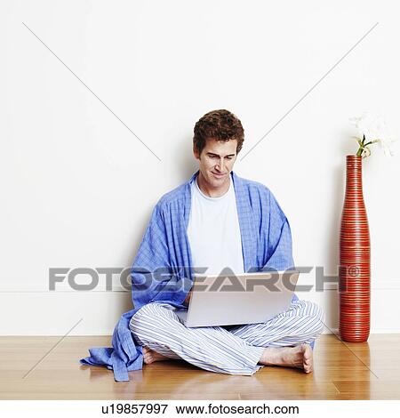 Mature man sitting cross-legged on the floor and using a laptop View Large Photo Image Stock Photo - Mature man sitting cross-legged on the floor and using a laptop. Fotosearch