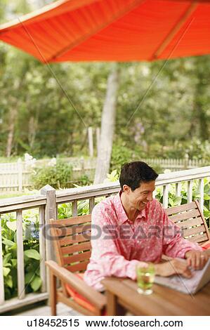 Stock Photography - Mature man sitting in a chair and using a laptop. Fotosearch