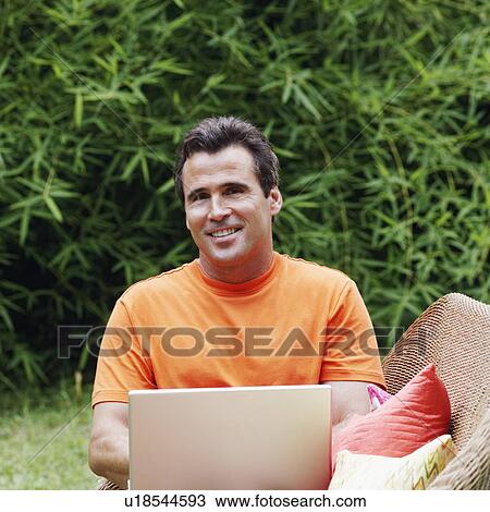 Mature man with a laptop sitting on a couch View Large Photo Image Stock Image - Mature man with a laptop sitting on a couch. Fotosearch