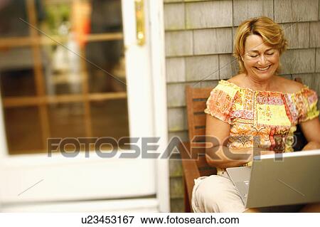Stock Photo - Mature woman using a laptop and smiling. Fotosearch