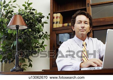 Stock Image - Portrait of a businessman using a laptop. Fotosearch