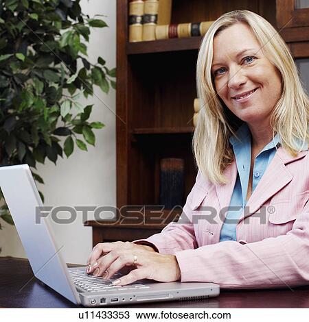 Portrait of a businesswoman working on a laptop and smiling View Large Photo Image Stock Image - Portrait of a businesswoman working on a laptop and smiling. Fotosearch