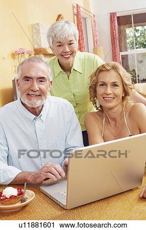 Stock Image - Portrait of a mature man and a senior woman sitting in front of a laptop and smiling. Fotosearch