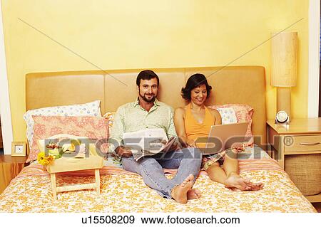Portrait of a mature man sitting on the bed with a mature woman using a laptop beside him View Large Photo Image Stock Photo - Portrait of a mature man sitting on the bed with a mature woman using a laptop beside him. Fotosearch