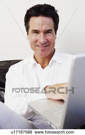 Stock Photo - Portrait of a mature man using a laptop and smiling. Fotosearch