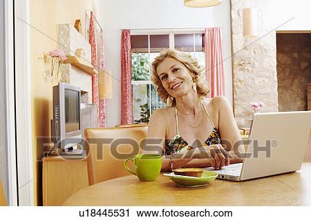 Portrait of a mature woman smiling in front of a laptop View Large Photo Image Stock Image - Portrait of a mature woman smiling in front of a laptop. Fotosearch