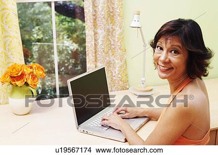 Portrait of a mature woman using a laptop and smiling View Large Photo Image Picture - Portrait of a mature woman using a laptop and smiling. Fotosearch