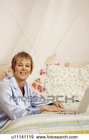 Portrait of a mature woman using a laptop and smiling View Large Photo Image Stock Photo - Portrait of a mature woman using a laptop and smiling. Fotosearch