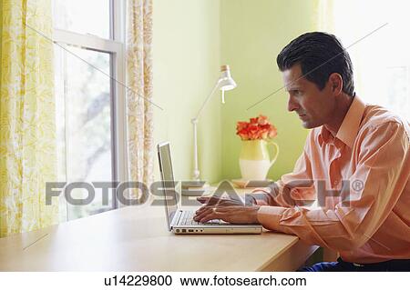 Stock Image - Side profile of a mature man using a laptop. Fotosearch